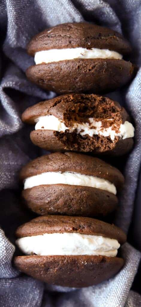 four whoopie pies lined up in a loaf pan lined with a blue linen napkin