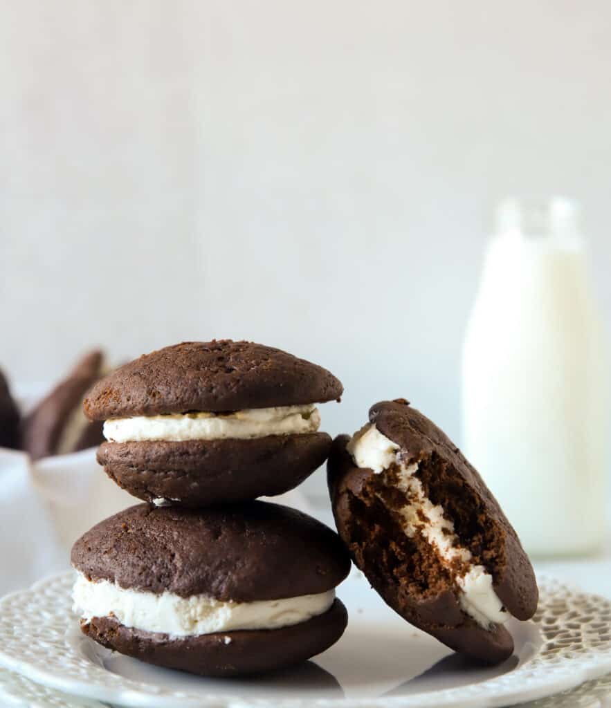 two chocolate whoopie pies stacked and one with a bite taken out of it leaning next to them
