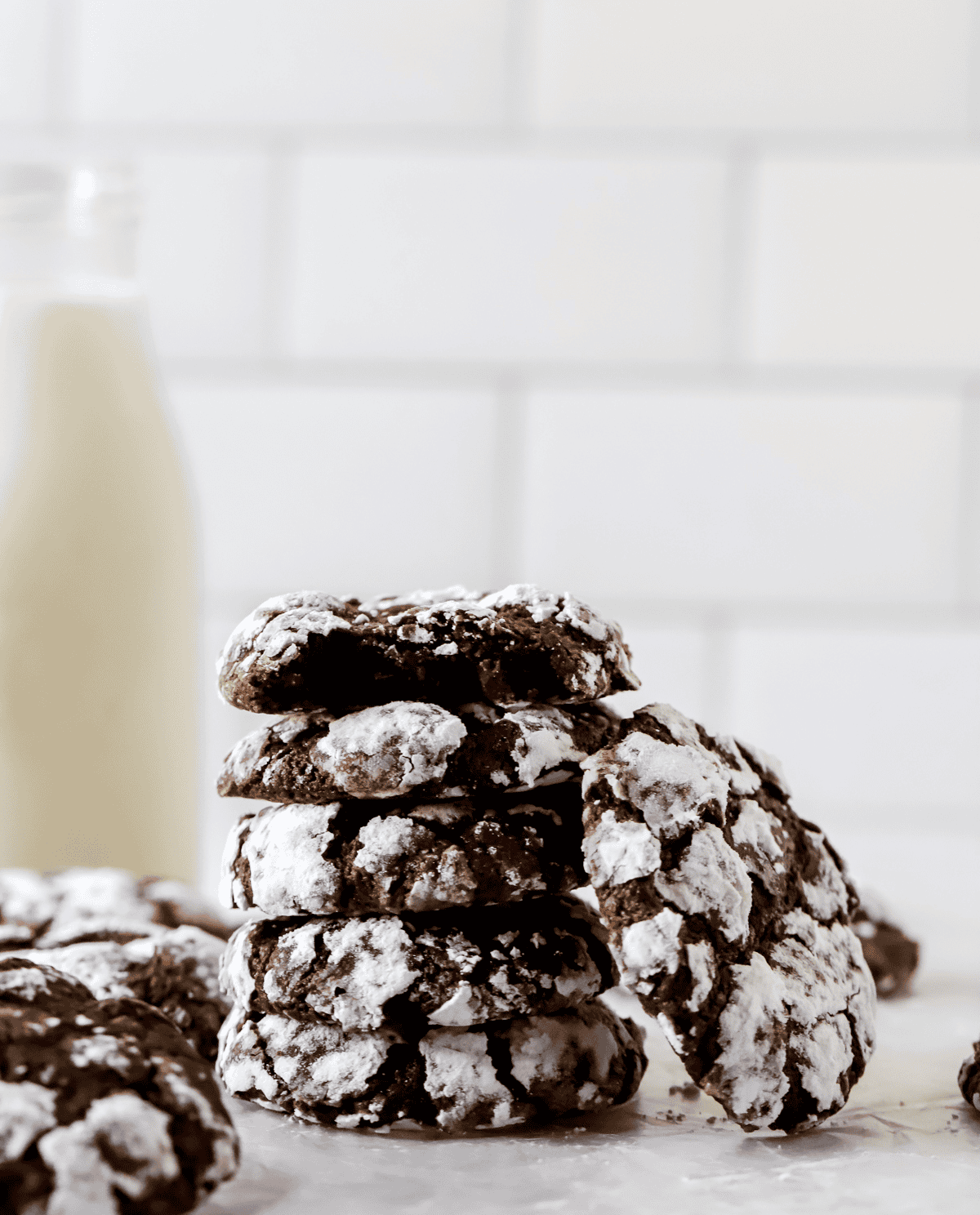 stack of chocolate crinkle cookies with a glass of milk behind them