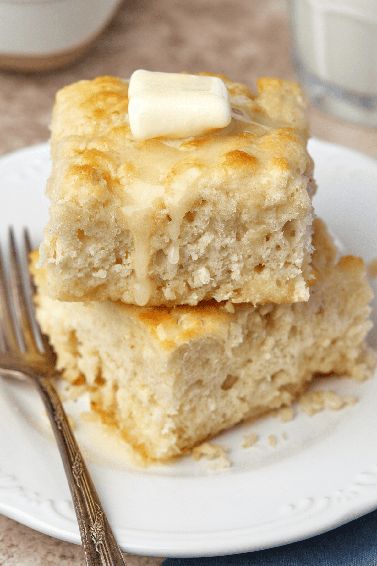 two homemade biscuits on a plate topped with butter
