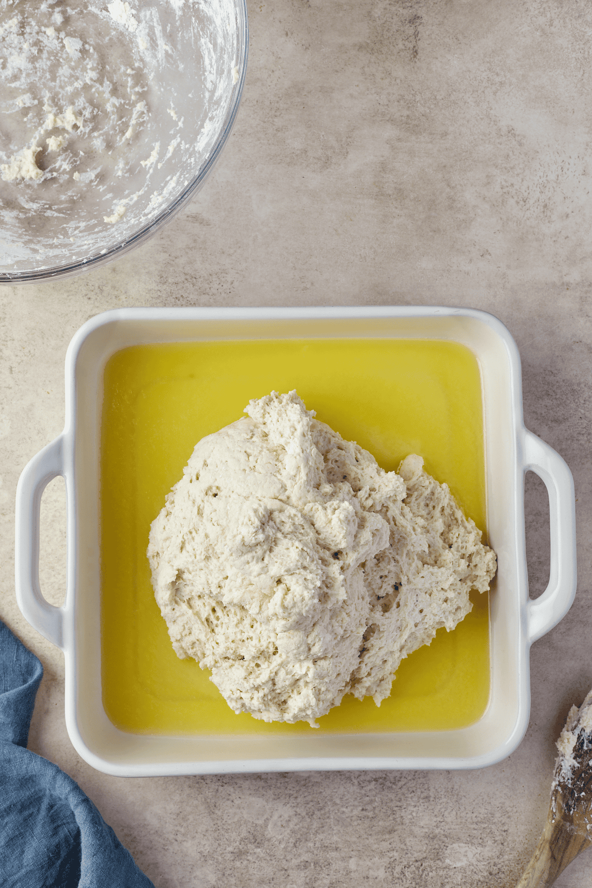 homemade biscuit dough placed on top of melted butter in a baking dish